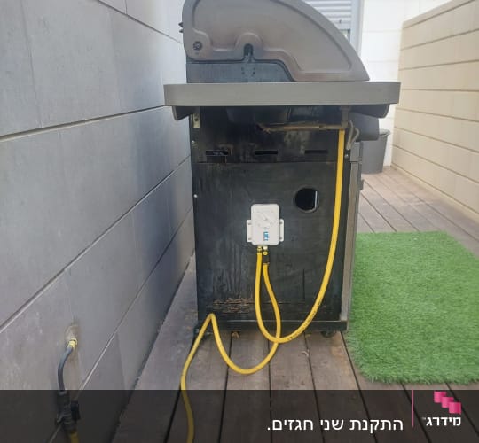 גריל גז מחובר לצינור גז צהוב על רצפת עץ